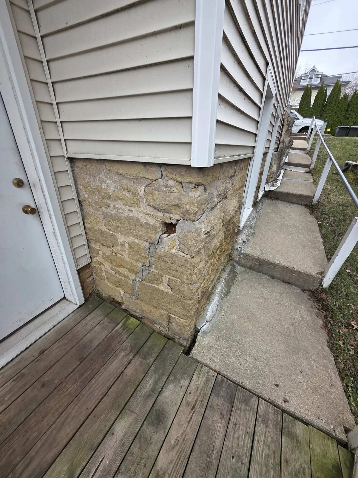 Cracked and settled concrete steps along the side of a house before replacement