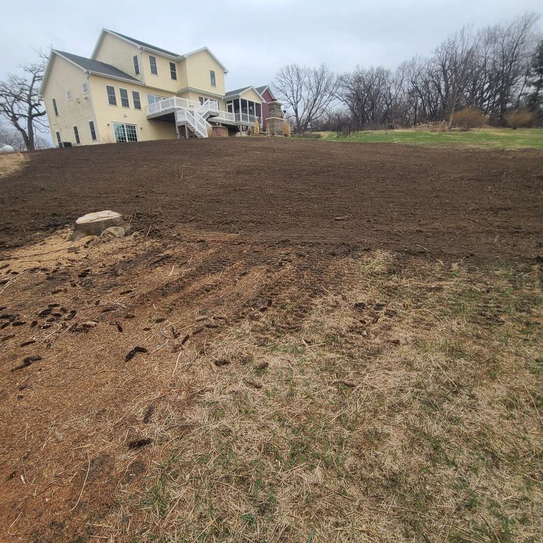 Sloped backyard graded smooth and ready for a new lawn behind a two-story home