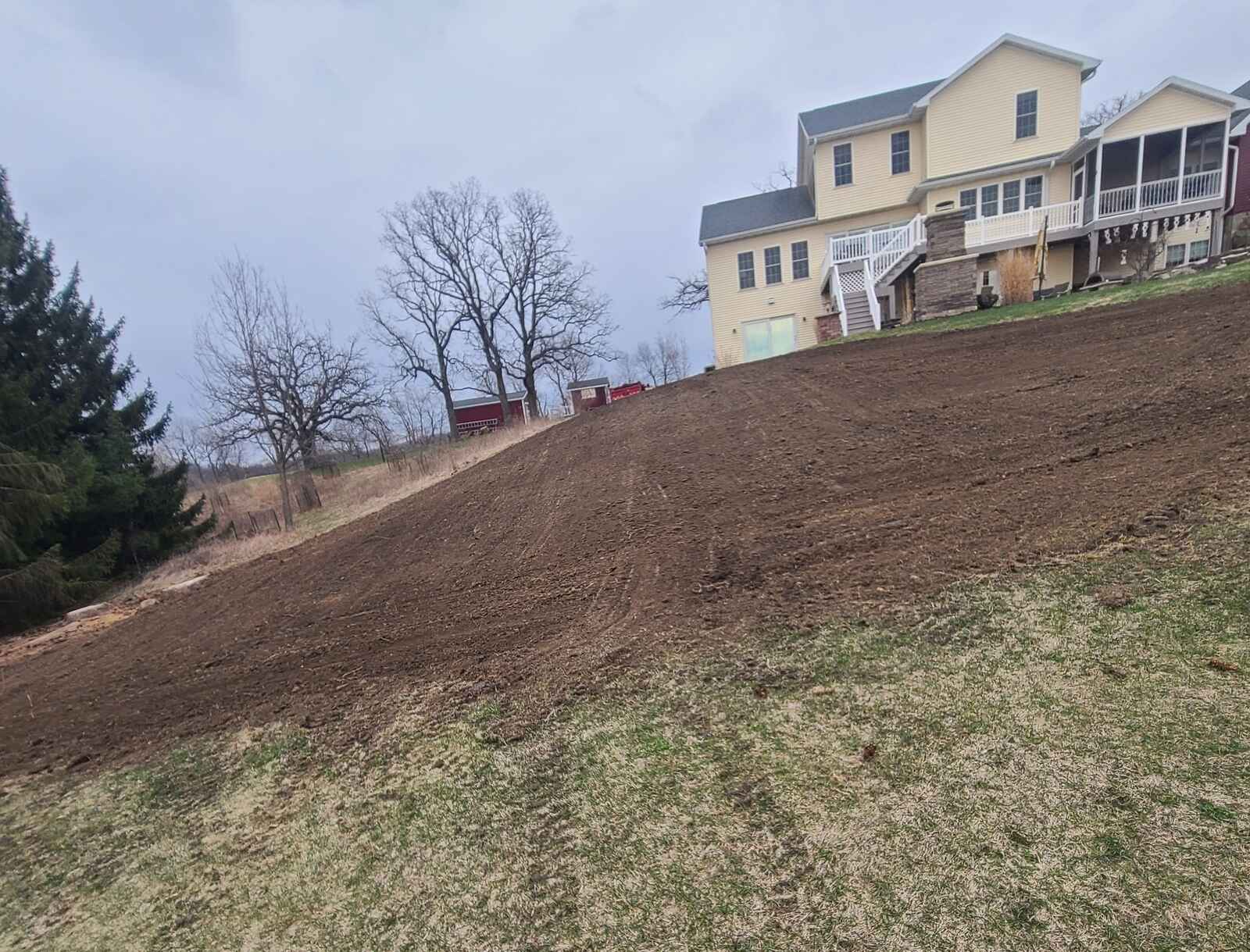 Hillside backyard graded with fresh topsoil, ready for a new lawn