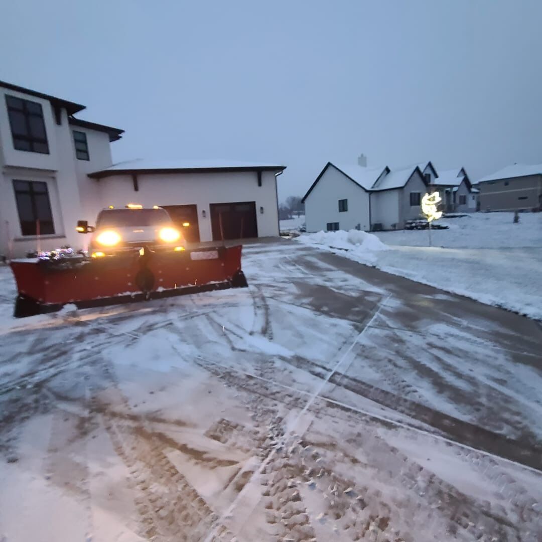 Plow truck clearing a driveway at dusk