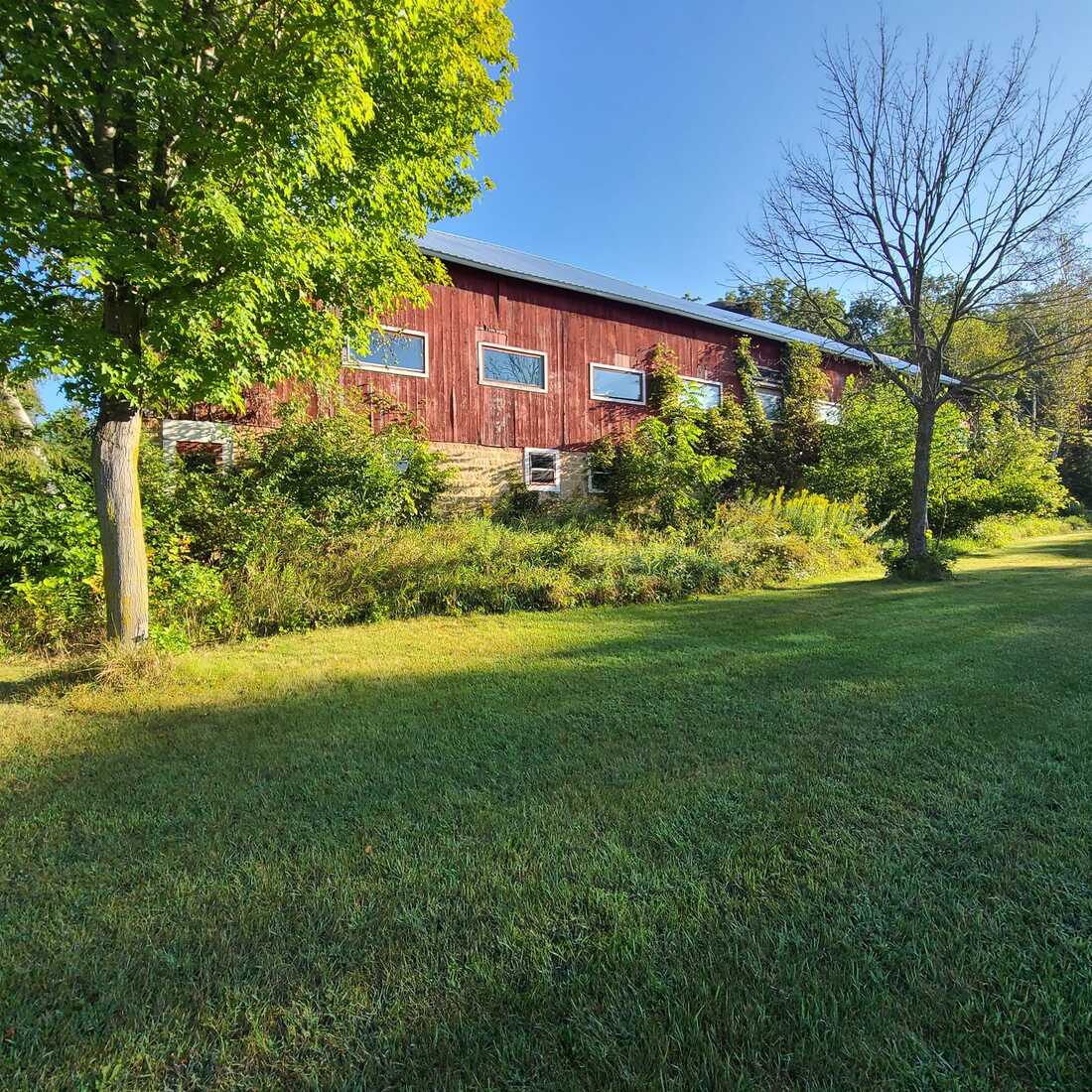 Mowed lawn in front of a long red barn in late-day light