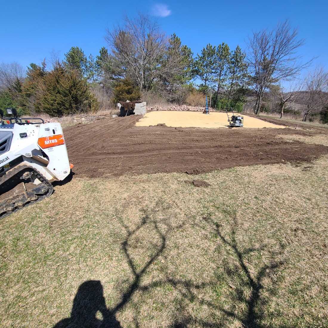 Compact track loader beside a compacted gravel pad